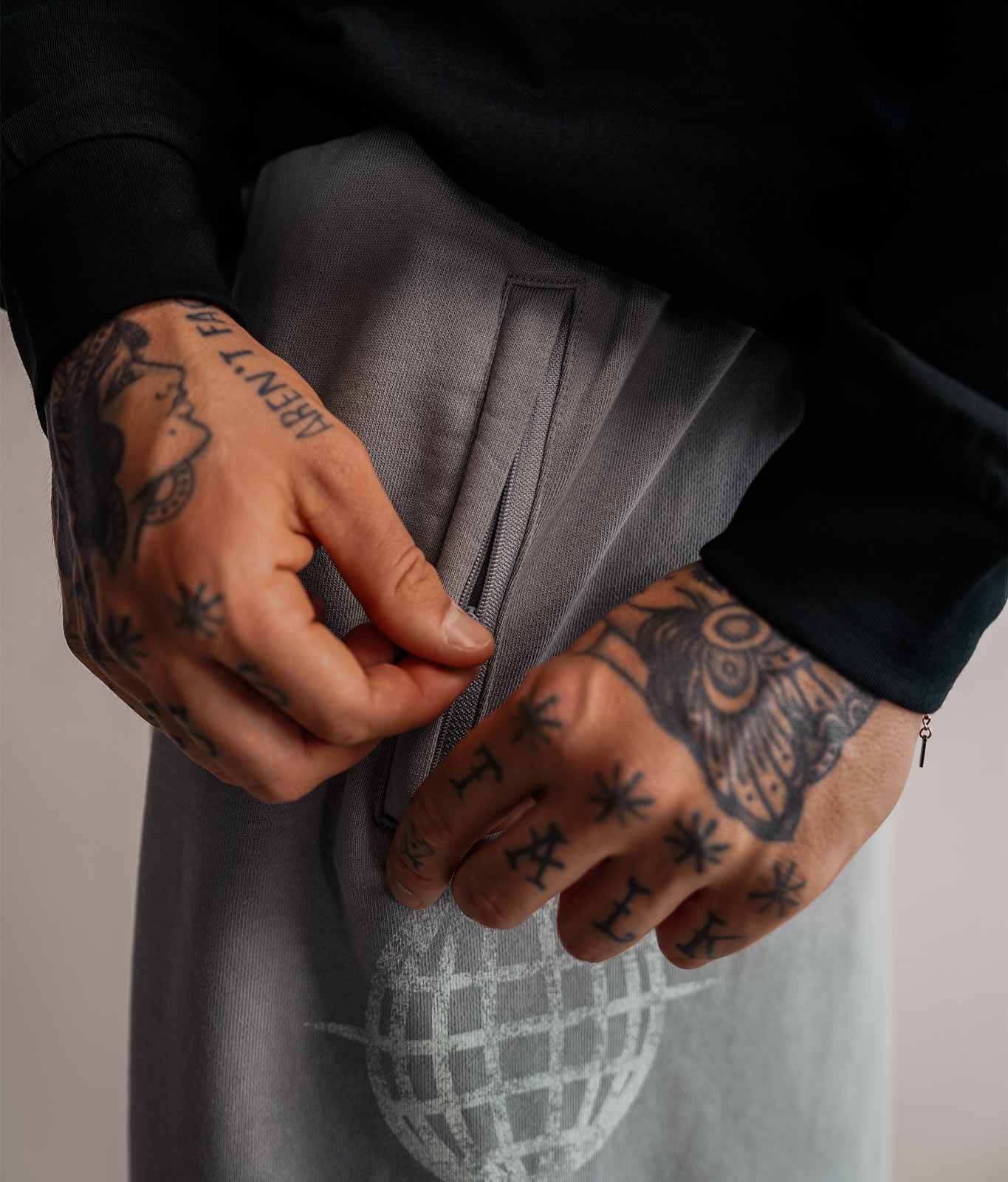 Nahaufnahme der Reißverschlusstasche Ton in Ton an grauer 3/4 Sweatshorts