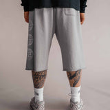 Rückansicht der grauen 3/4 Shorts Herren mit Gesäßtasche und Logo-Print