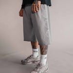 3/4 Shorts Herren in Grau mit Logo-Print seitlich am Bein, getragen mit weißen Tellem Socken