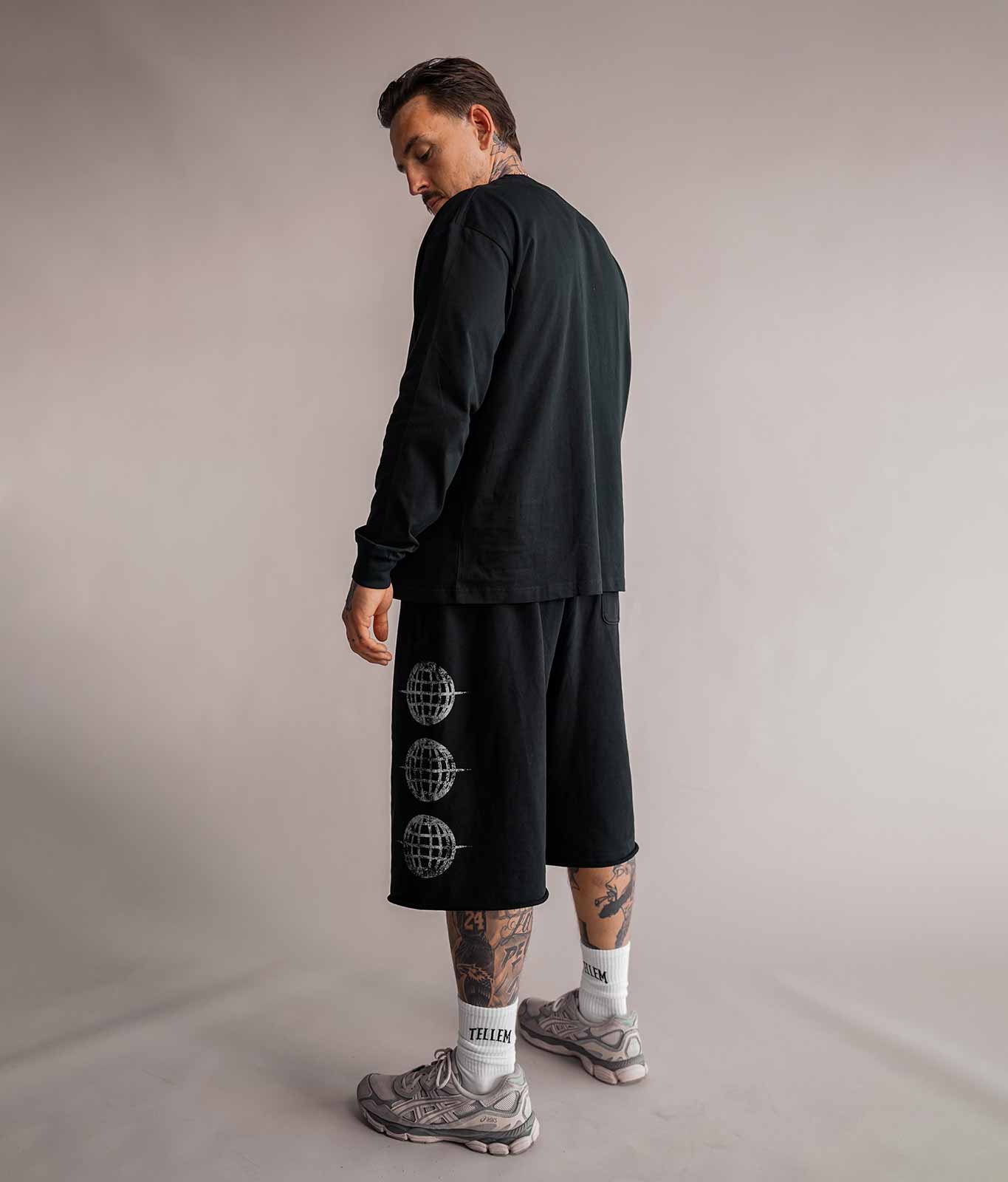 Model von hinten in schwarzer 3/4 Shorts und schwarzem Longsleeve, Basketball-Streetwear von Tellem