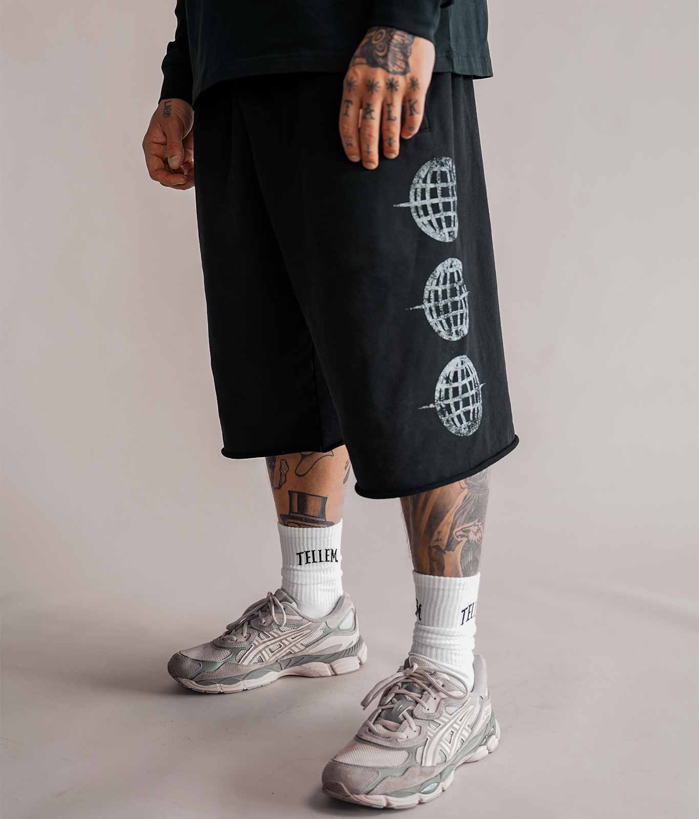 3/4 Shorts Herren in Schwarz mit Logo-Print seitlich am Bein, getragen mit weißen Tellem Socken