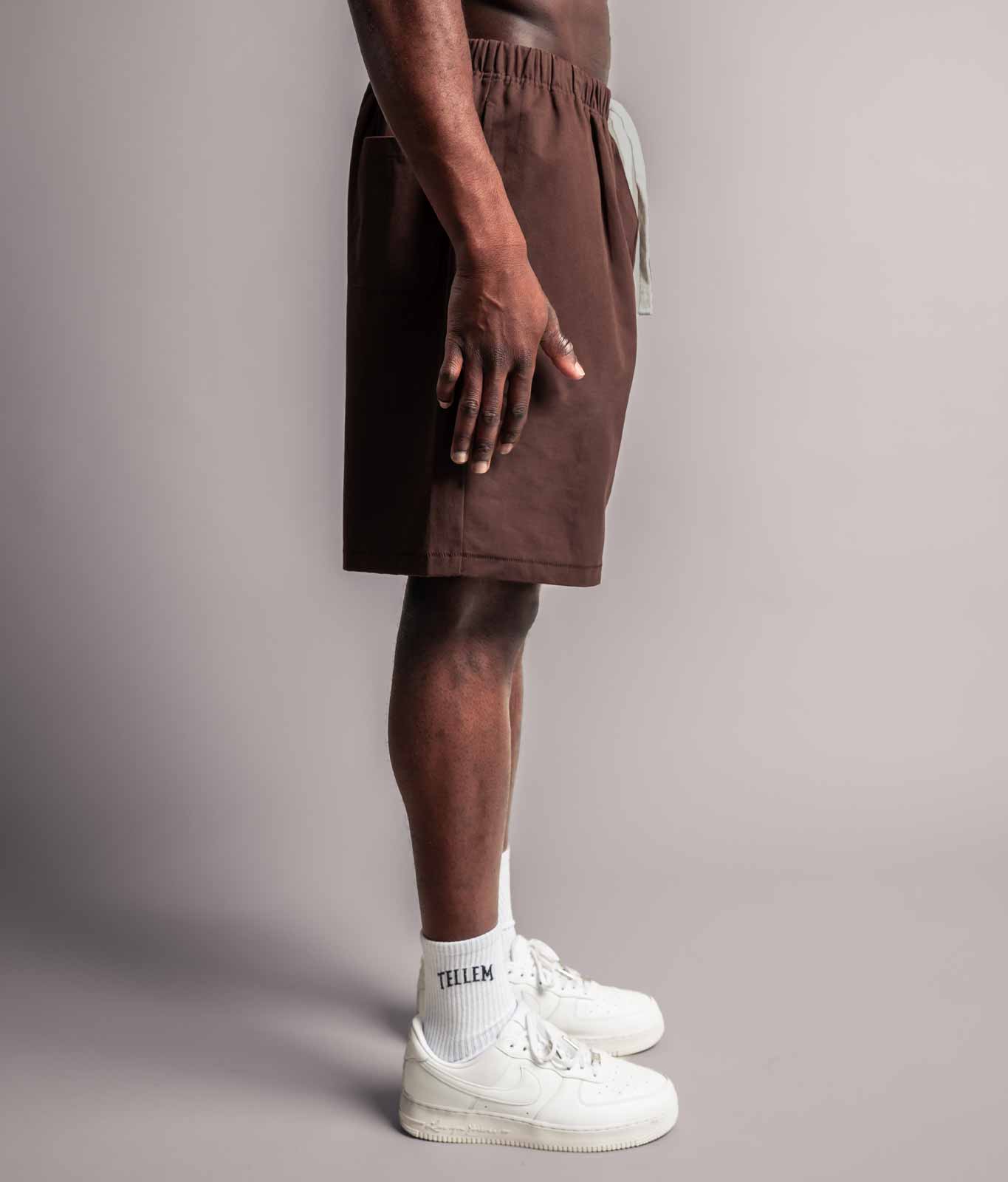 Model in seitlicher Ansicht trägt die braune TELLEM Baumwoll Shorts aus Cotton Twill mit lockerem Fit.