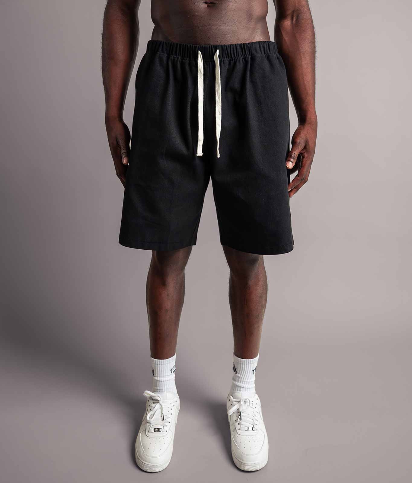 Model trägt die schwarzen TELLEM Baumwoll Shorts aus Cotton Twill mit lockerem Fit.