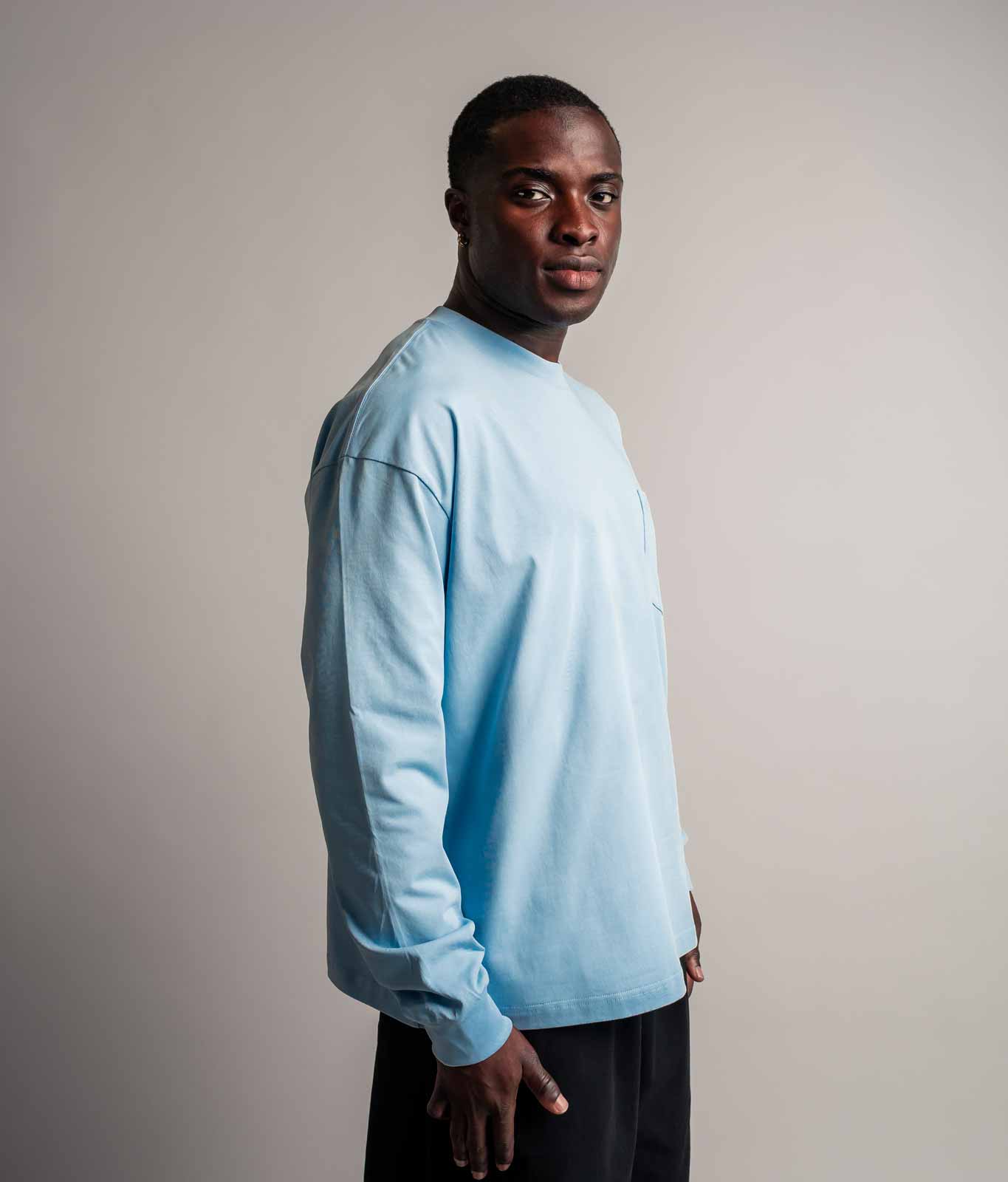Model trägt TELLEM Longsleeve Pocket in Ice Blau, Seitenansicht mit Brusttasche