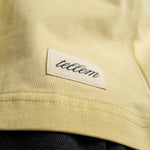 Nahaufnahme gewebter TELLEM Patch am Saum des Longsleeve Pocket Lemon