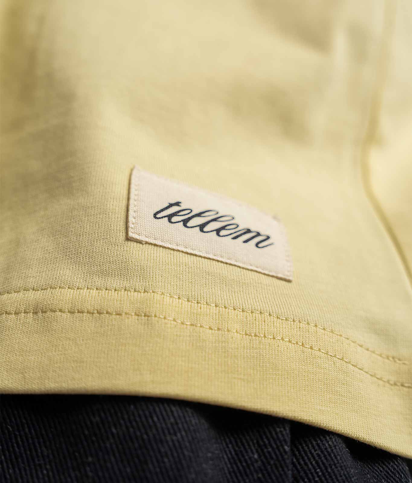 Nahaufnahme gewebter TELLEM Patch am Saum des Longsleeve Pocket Lemon