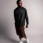 Model trägt das schwarze TELLEM Longsleeve aus 100 % Baumwolle mit lockerem Fit zu kurzer Hose