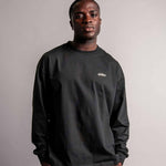 Model trägt das schwarze TELLEM Longsleeve aus 100 % Baumwolle mit lockerem Fit.