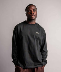 Model trägt das schwarze TELLEM Longsleeve aus 100 % Baumwolle mit lockerem Fit.
