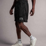 Model trägt TELLEM Mesh Shorts Move in Schwarz, Seitenansicht mit Logo am Bein
