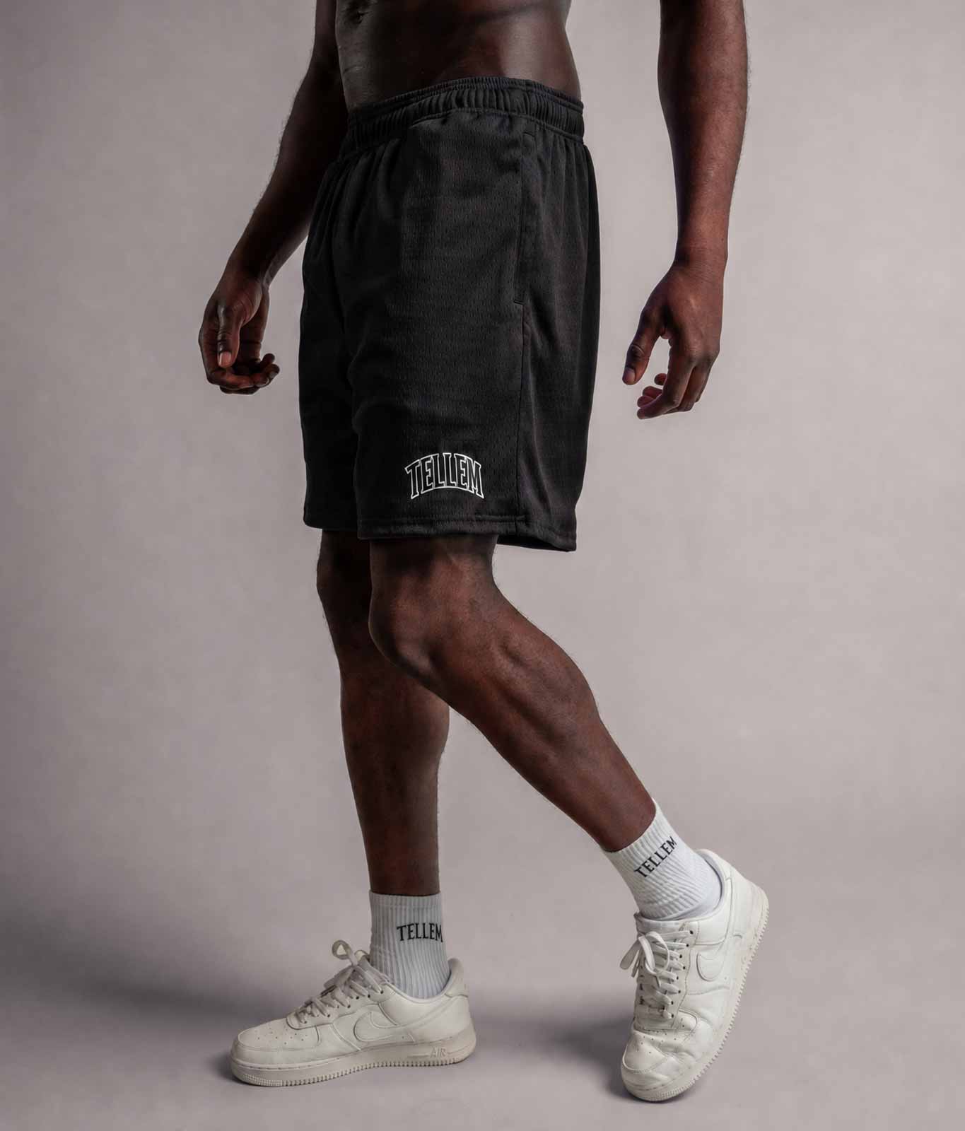 Model trägt TELLEM Mesh Shorts Move in Schwarz, Seitenansicht mit Logo am Bein