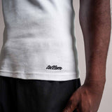 Detailaufnahme des gestickten TELLEM Signature Logos am Saum des weißen Tanktops. LEO